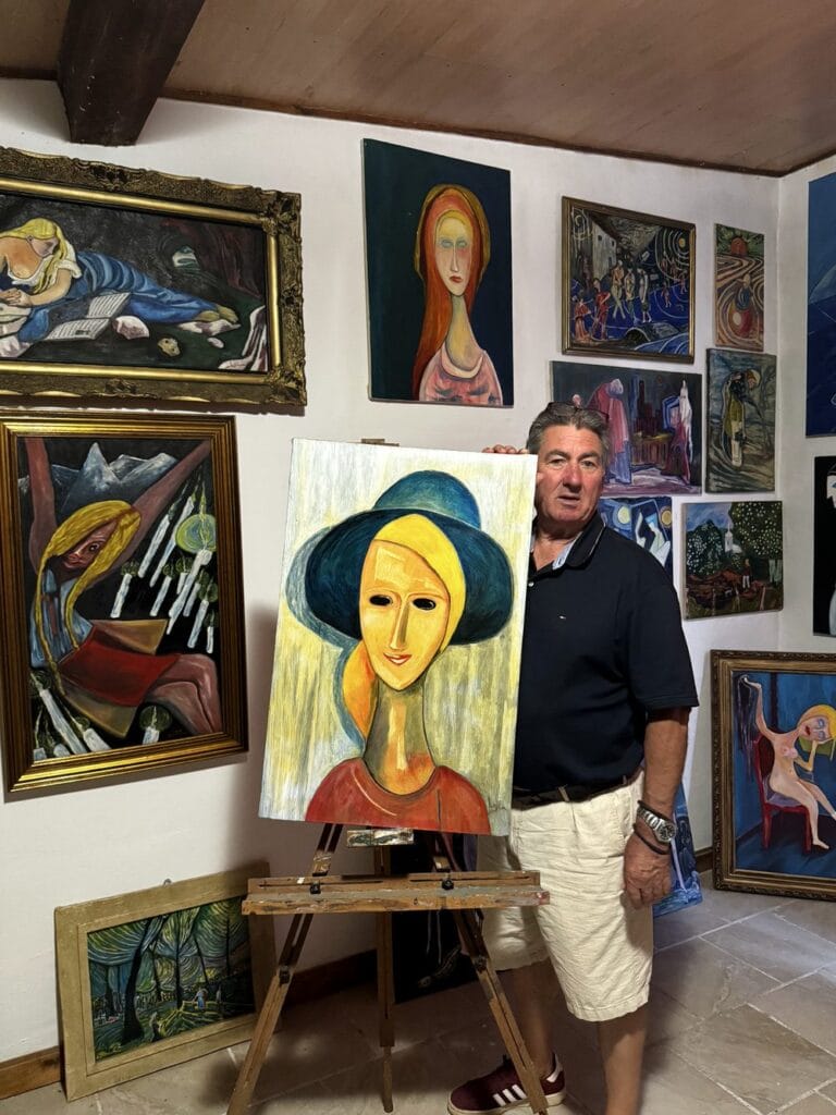 Luis Ludovic Garcia Camarero ține pe șevalet un portret cu pălărie albastră, în galeria de artă din Frata